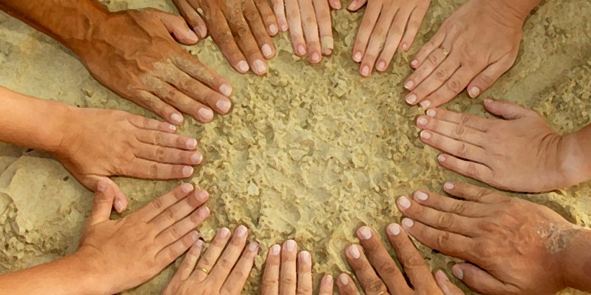 Photo of a circle of hands in the sand
